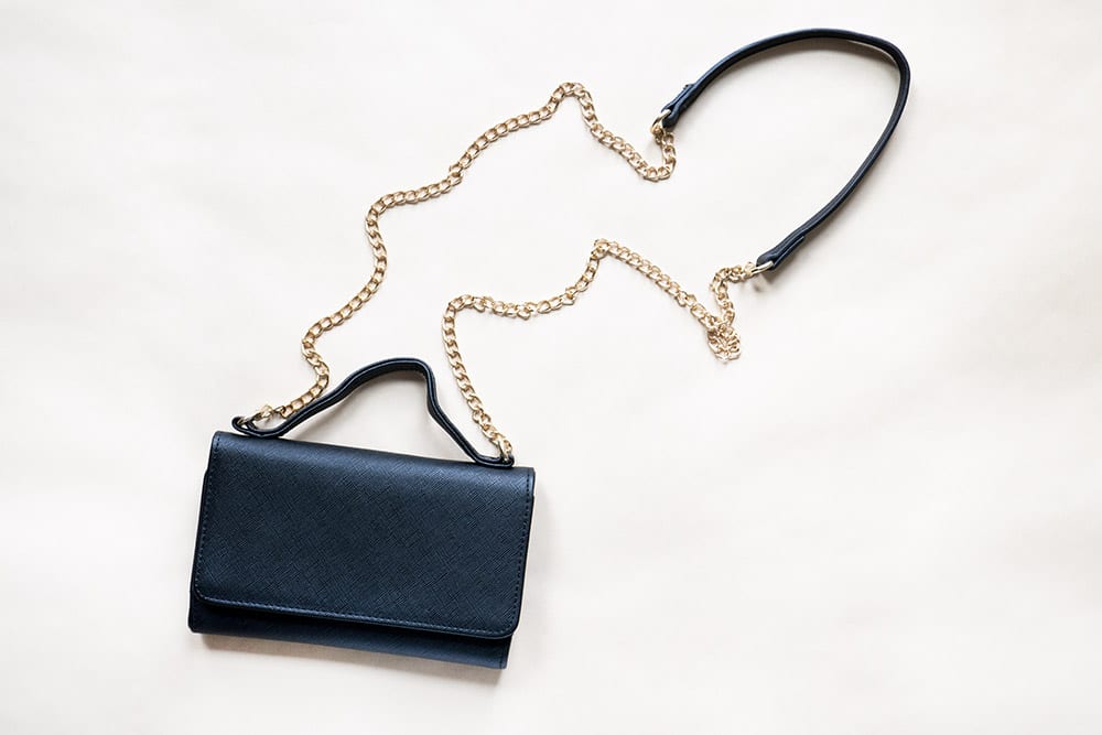 black cross body bag with gold strap flat lay